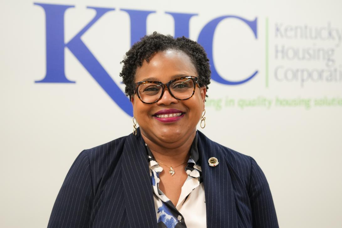 A woman, Annissa M. Franklin, wearing glasses and blazer smiles in front of a Kentucky Housing Corporation logo.